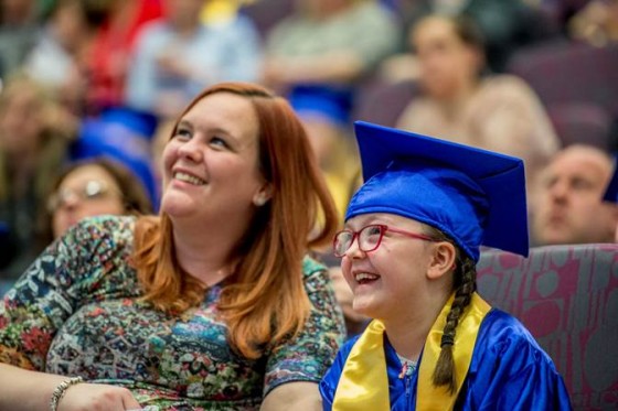 Audience members smile as they watch the CU graduation ceremony