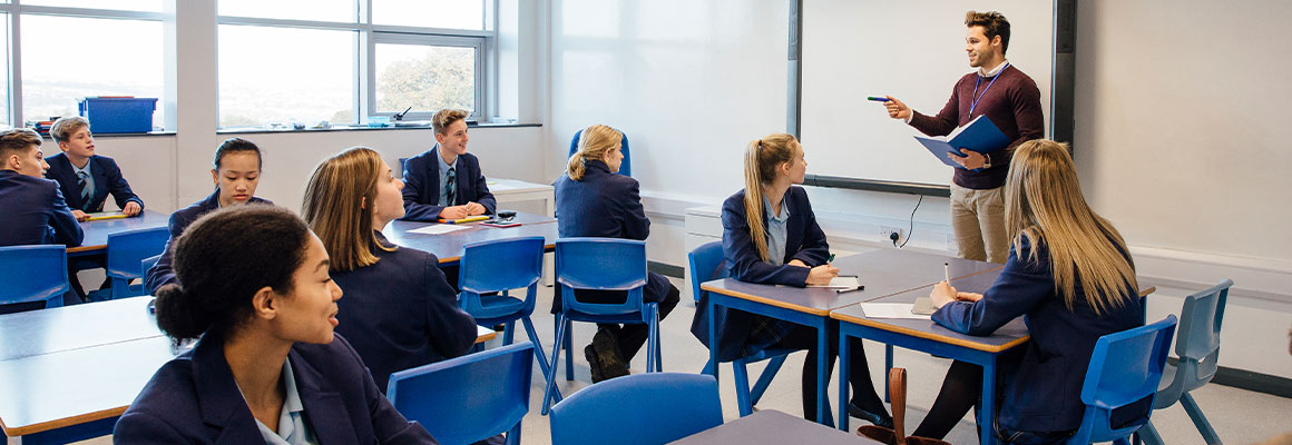 A classroom of learners listening to the member of staff at the whiteboard